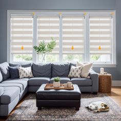 a living room filled with furniture and a large window covered in blind shades over the windows