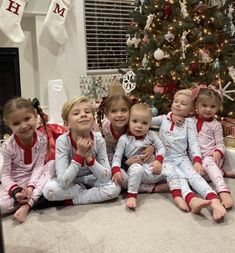 a group of children sitting in front of a christmas tree