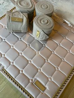 three rolls of toilet paper sitting on top of a pink quilted suitcase with gold hardware