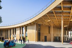 children's play area in front of an open building with wooden roof and curved walls