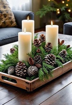 a tray with candles and pine cones in it sitting on a wooden table next to a couch