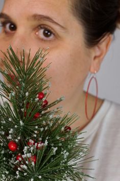 a woman holding a fake christmas tree in front of her face