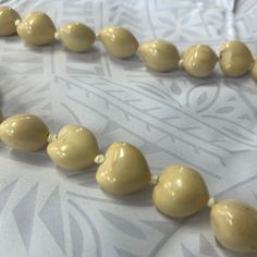 a close up of a necklace made out of chocolate beads on a bed sheet with a white background