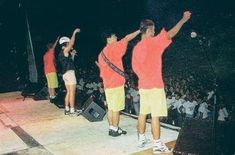 three people on stage with their arms in the air and one person holding a tennis racquet