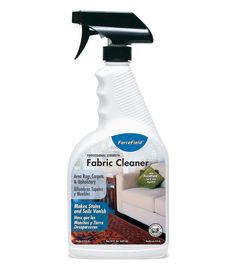 a bottle of fabric cleaner sitting on top of a white table next to a couch