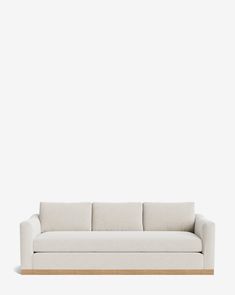 a white couch sitting on top of a wooden table in front of a white wall