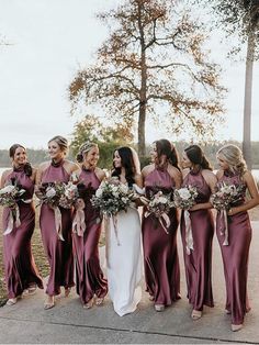 a group of women standing next to each other wearing dresses and holding bouquets in their hands