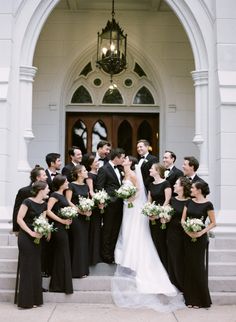 a bride and groom with their bridal party in front of an ornate doorway at the church