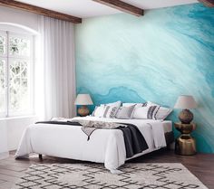 a large bed sitting in a bedroom next to a wall painted with blue and white swirls