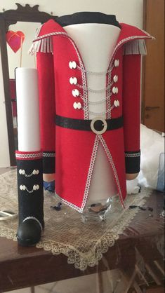 a red and black costume is sitting on a table next to a white candle holder