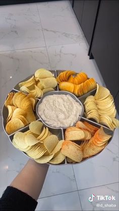 a platter filled with chips and dips on top of a marble countertop