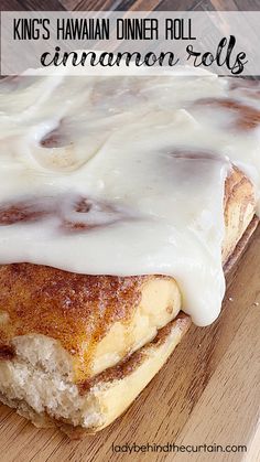 a cinnamon roll with icing sitting on top of a wooden cutting board