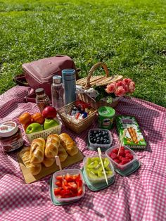 a picnic blanket is laid out on the grass with various foods and drinks in it