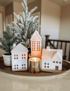 small white houses sitting on top of a wooden tray next to a potted plant