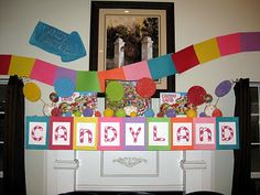 there is a candy bar decorated with balloons and streamers on the mantle in this room