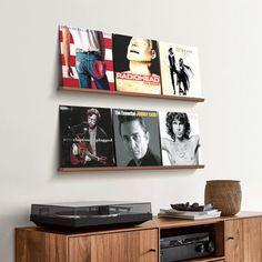 there are two wall mounted pictures on the wall above a record player and an entertainment center