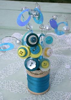 a vase filled with buttons and thread on top of a table