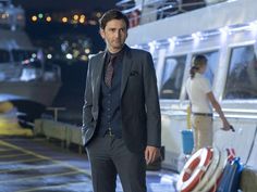 a man in a suit standing next to a boat