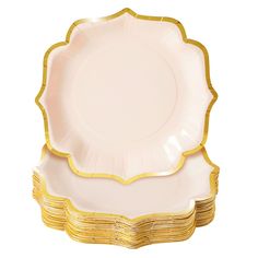 a stack of white and gold plates on a white background with one plate in the shape of a scalloped flower