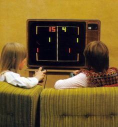 two children sitting in front of a television playing an old school video game on the wall