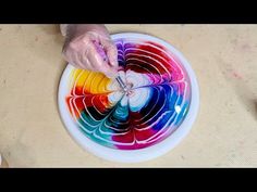 a person is painting on a plate with different colors