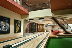 a bowling alley in a modern home with pool and spiral staircases to the second floor