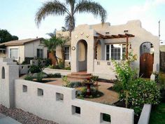 a white house with palm trees in the front yard and landscaping on the other side