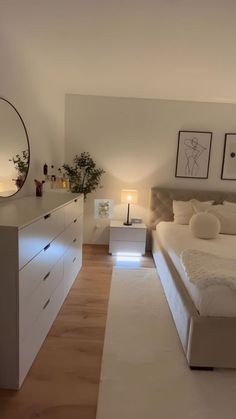 a bedroom with a bed, dresser and mirror on the wall next to each other