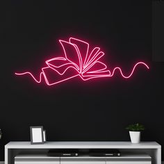 a neon sign that is on the side of a wall next to a table with a plant