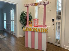 a pink and white striped lemonade stand in front of a door