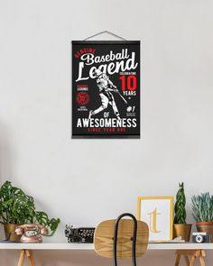 a baseball poster hangs on the wall above a desk with a chair and potted plant