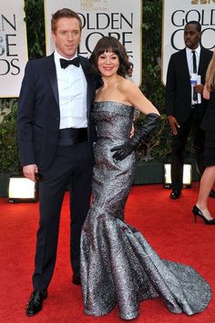 a man and woman in formal wear standing on a red carpet