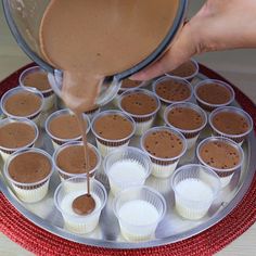 someone is pouring chocolate into cupcakes on a tray