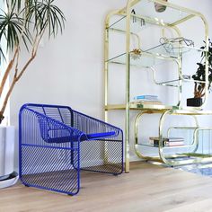 a blue shopping cart sitting next to a tall plant in a room with white walls