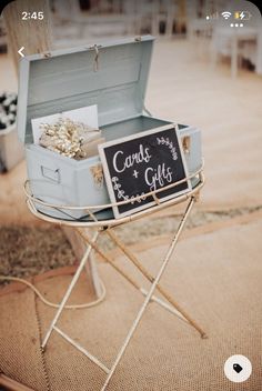 an open suitcase sitting on top of a table next to a chalkboard sign that says candie and gifts