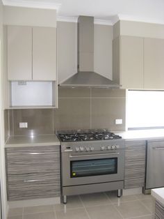 a stove top oven sitting inside of a kitchen next to white cupboards and drawers