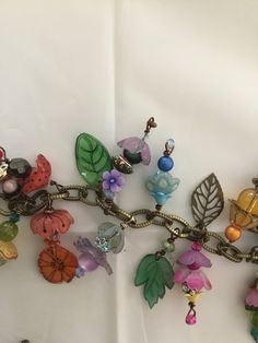 a bunch of charms that are on a white table cloth with some flowers and leaves attached to them