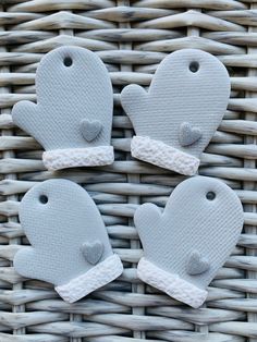 three oven mitts are sitting on a wicker basket with two hearts in the middle