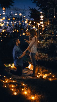 two people holding hands in the dark surrounded by lit up lanterns and trees at night