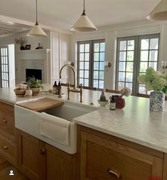 a large kitchen with an island sink and two lights hanging from the ceiling above it