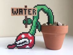 a potted plant sitting next to a sign that says water and a pixel art piece