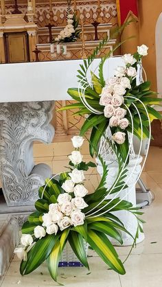 white flowers and greenery are arranged on the floor in front of a fireplace mantel