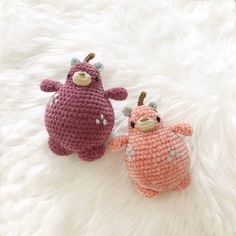 two crocheted animals laying on top of a white rug