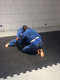 a man in blue jiu - jik gear is on the floor with his hands behind his head