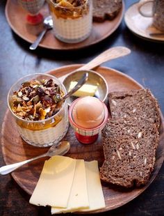 an assortment of food is on a plate with bread, butter and jam in small bowls