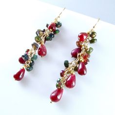 "Stunning smooth red rubies and gorgeous black faceted Ethiopian opals are paired up to create these striking earrings. The ruby gemstones are a nice generous size measuring approximately 5-8 mm. The gems are wrapped gold filled wire and pins and then attached to a length of gold filled chain. The earrings measures 2 1/8\" from the top of the ear wires." Red Dangle Jewelry With Gemstone Accents, Red Gemstone Accented Drop Earrings, Red Faceted Garnet Earrings, Cluster Jewelry, Ethiopian Opal Earrings, Coral And Gold, Gold Filled Earrings, Opal Earrings, Ruby Gemstone