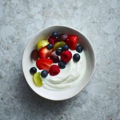 a bowl filled with yogurt and fruit on top of a marble countertop