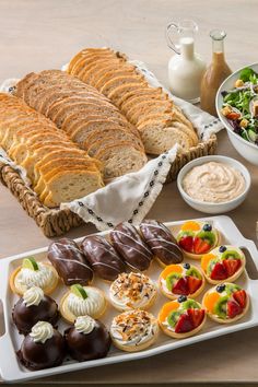 an assortment of pastries and dips on a tray next to bowls of salad