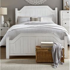 a white bed sitting in a bedroom next to a dresser with drawers and a mirror on the wall