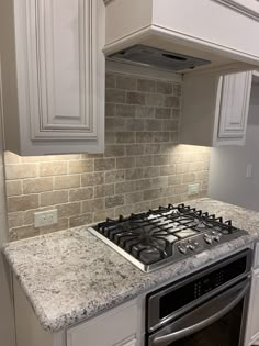 a stove top oven sitting inside of a kitchen next to white cabinets and counter tops